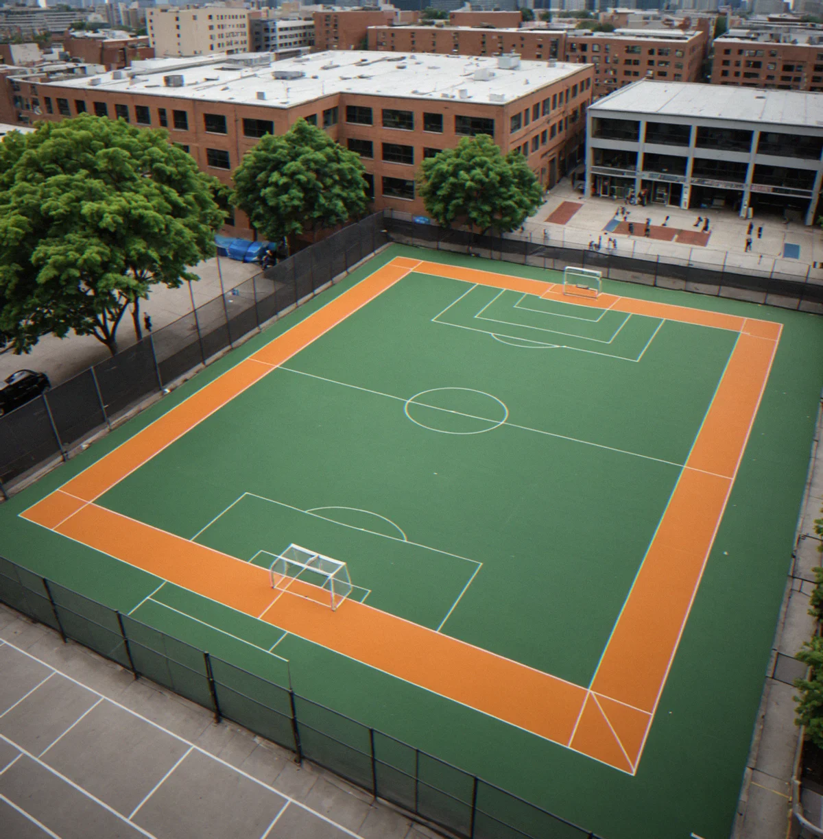 Urban futsal court nestled between city buildings with foot traffic nearby